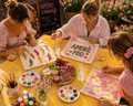 mains qui peignent un tote bag en toile avec de la peinture colorée, lumière dorée du soir